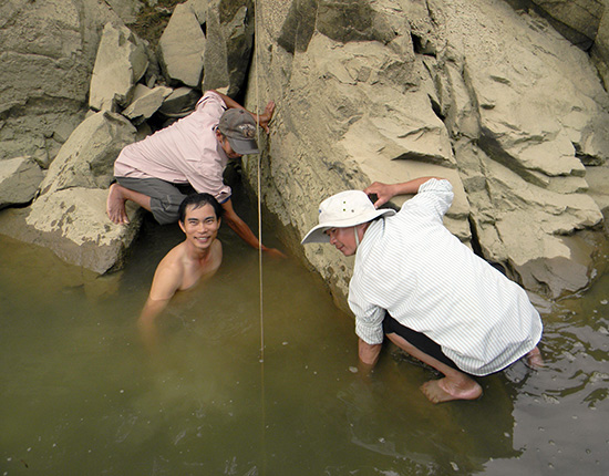 Các nhà nghiên cứu đang tiến hành đo đạc bia ký Chăm trên sông Thu Bồn. Ảnh: N.T.Hỷ
